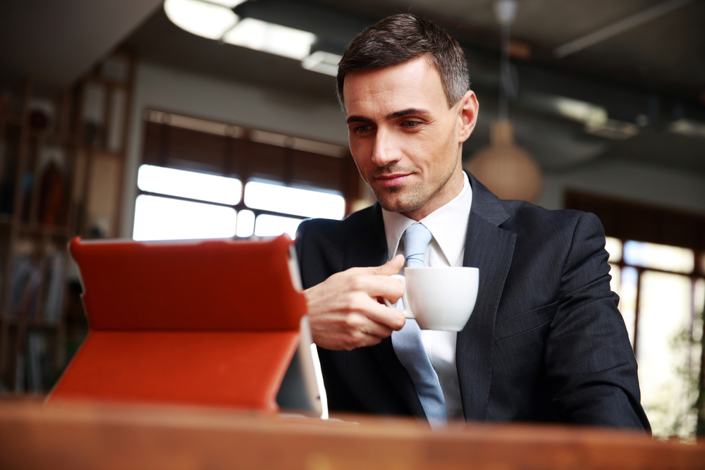 Businessman drinking coffee and reading news in cafe-1
